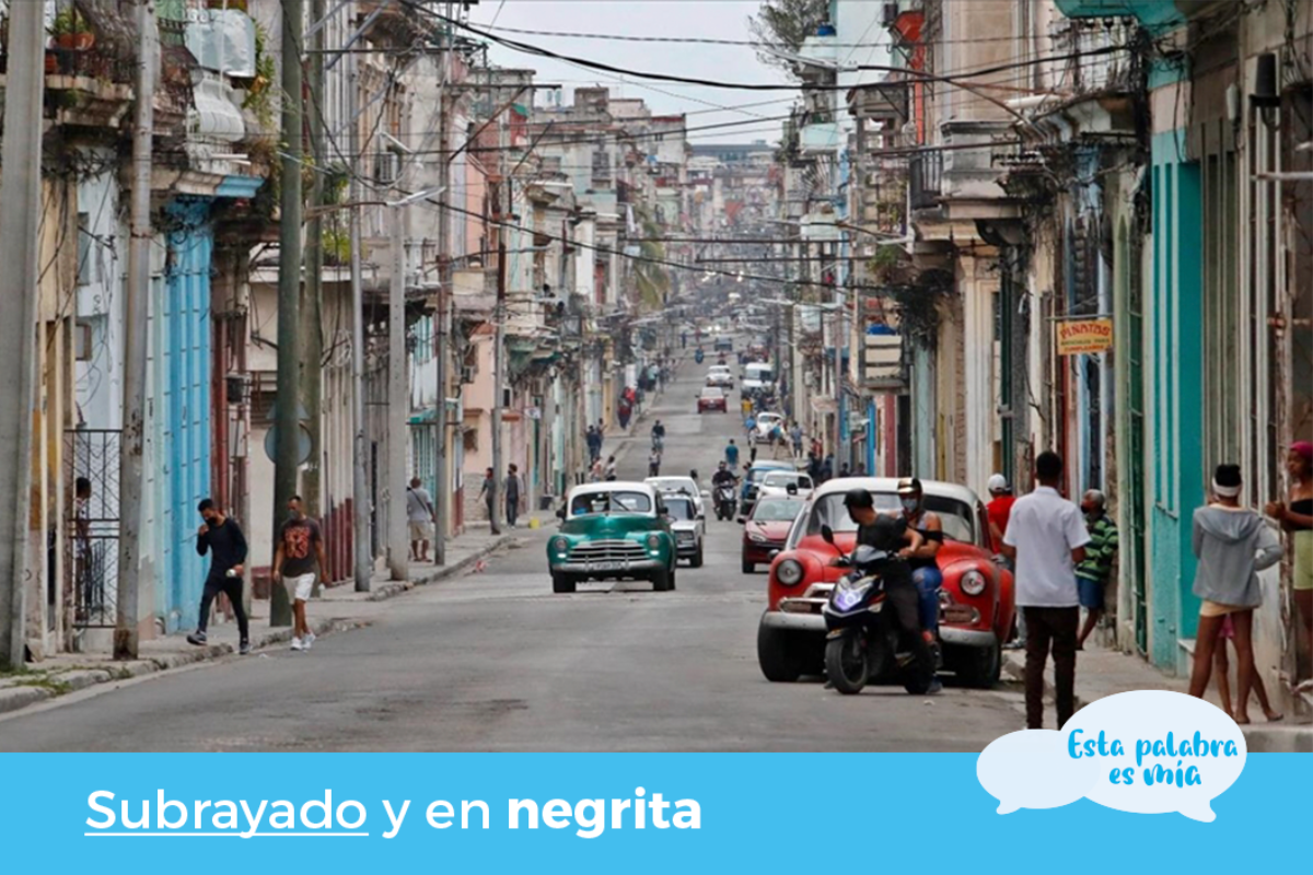 Una larga y estrecha calle de La Habana bordeada de edificios de dos plantas. Se ven algunos …